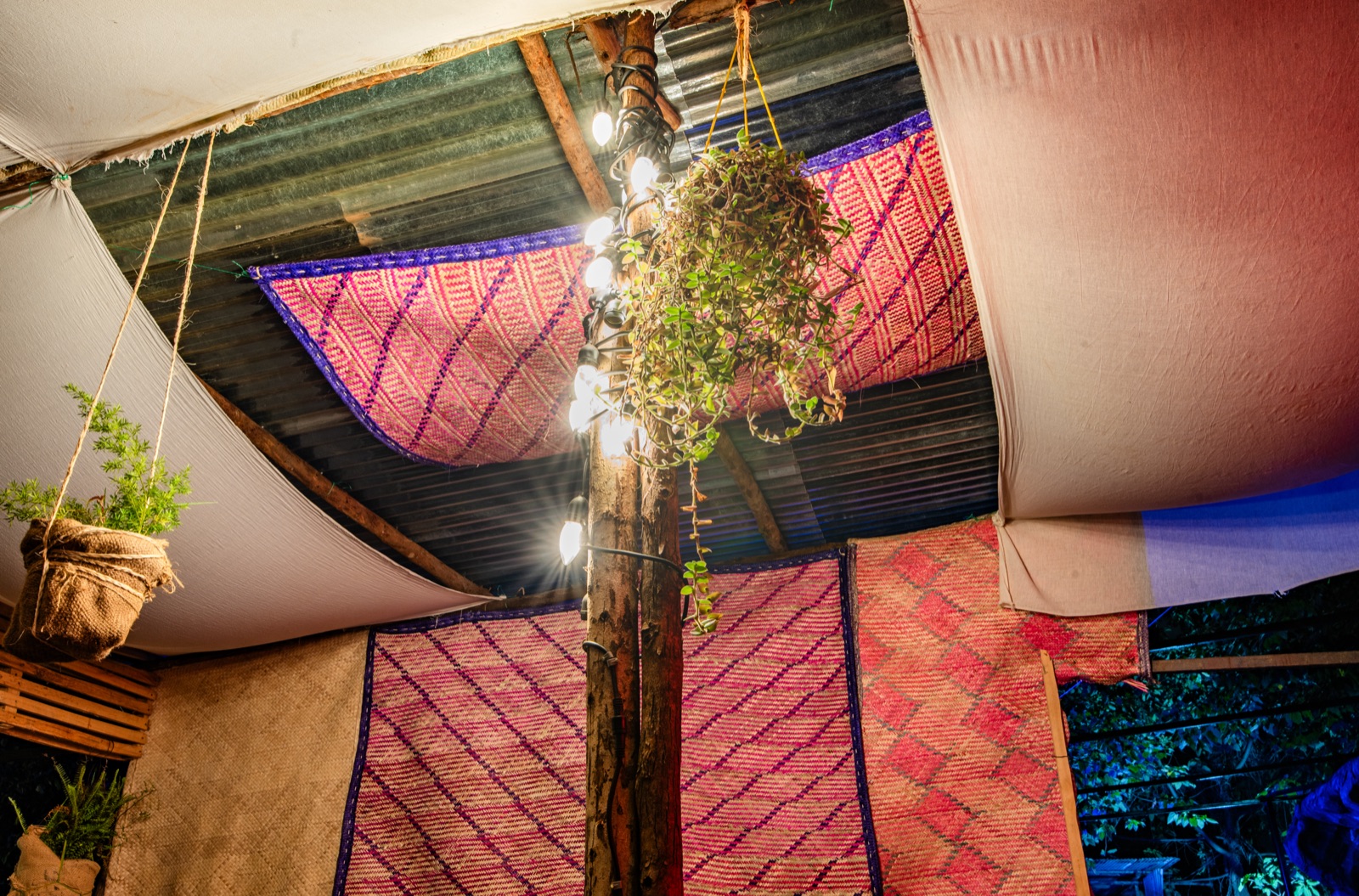 Woven mats and string lights across the garden canopy